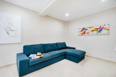 a blue couch in a white room with paintings at Vivenda das Conchas - Just 50 Meters from the Beach in Quarteira