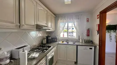 a kitchen with white cabinets and a stove top oven at Casa Vela São Rafael in Albufeira