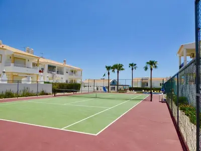 a tennis court with a tennis net and palm trees at Casa Vela São Rafael in Albufeira