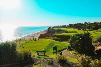 a golf course with a bench and the ocean at Vale do Lobo 5 Bed Villa with Large Pool overlooking Golf Course in Almancil