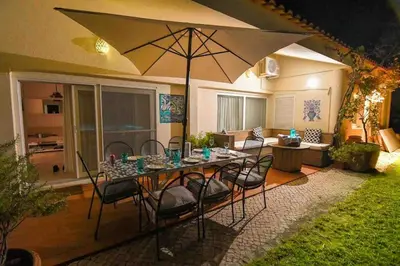 a table with chairs and an umbrella in a yard at Vale do Lobo 5 Bed Villa with Large Pool overlooking Golf Course in Almancil