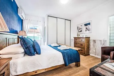 a bedroom with a large bed with blue walls at Casa Alfazema in Albufeira