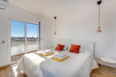 a bedroom with a large white bed with orange pillows at Apart OCEAN DRIVE - Oura - Jacuzzi - BY BEDZY in Albufeira