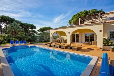 a swimming pool in front of a house at Villa Cristina in Quarteira