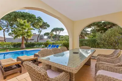 a patio with a table and chairs and a swimming pool at Villa Cristina in Quarteira
