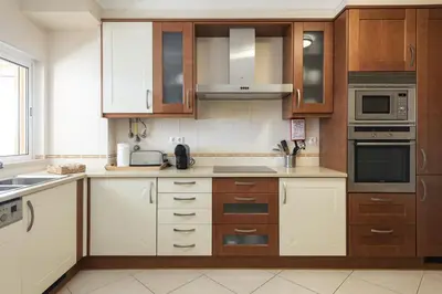 a kitchen with brown and white cabinets and appliances at Praia Village I - Peaceful condominium by HD in Vilamoura