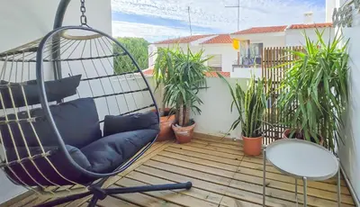 a swinging chair on a balcony with plants at Green Balcony Holiday Work Remote Big Apartment in Albufeira