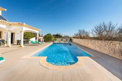 a swimming pool in a backyard with a stone wall at Villa Agapito in Terras Novas