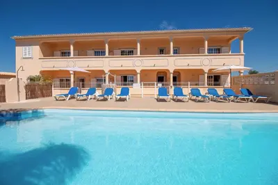 a swimming pool with blue chairs and a building at Casa Laranjal in Albufeira