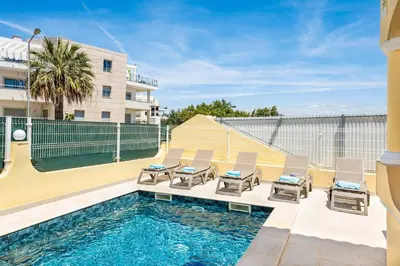 a swimming pool with chairs next to a building at Villa Alice Albufeira in Albufeira