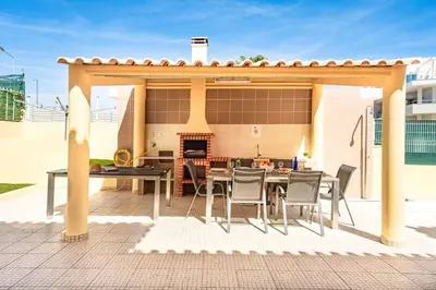 a patio with a table and chairs and a fireplace at Villa Alice Albufeira in Albufeira