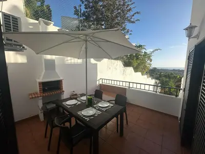 a table and chairs with an umbrella on a balcony at Cliff Enchantment - Pool and Sea View in Albufeira in Albufeira
