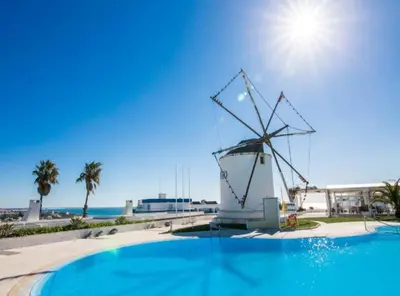 a windmill next to a swimming pool with the beach at Windmill Hill Luxury Apartment in Albufeira