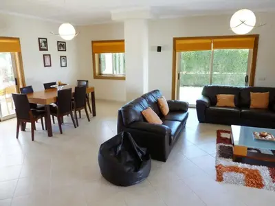 a living room with a black leather couch and a table at Villa Hugo - bright modern walk to restaurants in Albufeira
