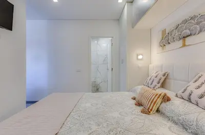 a white bedroom with a large bed with pillows at BELLAVISTA STUDIO - Modern and Renovated near Fishermen's Beach in Albufeira