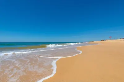 a beach with the ocean and a blue sky at Beach front right on the Sand Luxury semi-detached 3 bed Villa in Faro