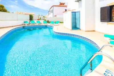 a swimming pool with blue chairs and a building at Villa Cesaltina in Guia