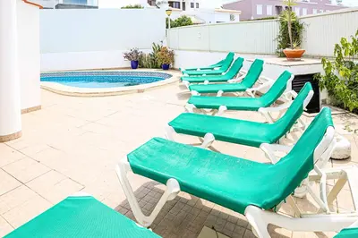 a row of green lounge chairs next to a swimming pool at Villa Cesaltina in Guia
