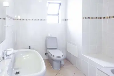 a white bathroom with a toilet and a sink at Villa Cesaltina in Guia