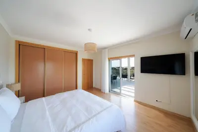 a bedroom with a large white bed and a flat screen tv at Penthouse Monte da Eira - Sunset in Albufeira