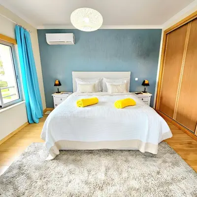 a bedroom with a large white bed with yellow pillows at T1 Albufeira Tranquilidade in Albufeira