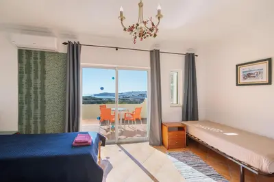 a bedroom with a bed and a balcony with a table at Breeze Villa - Adults Only in Albufeira