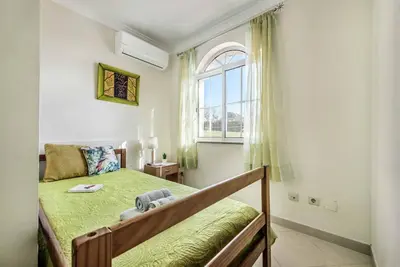 a bedroom with a bed with a green bedspread and a window at Villa Caty Catarina in Albufeira