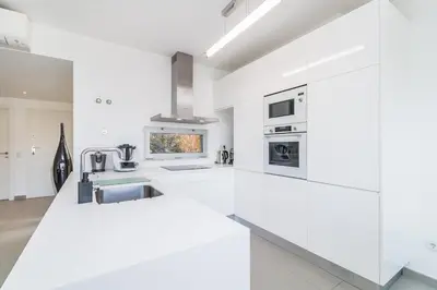 a white kitchen with white cabinets and appliances at Family Villa 3 Bedrooms private rooftop with Pool in Albufeira