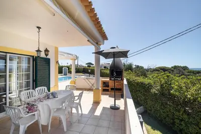 a patio with a table and chairs and an umbrella at Villa Império in Albufeira