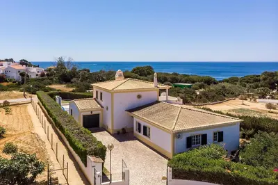 a large white house with the ocean in the background at Villa Império in Albufeira