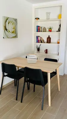a dining room table with chairs and a book shelf at Apartamento 5 min a pé da praia, com terraço ao sol, no 1º andar in Quarteira