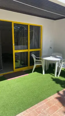 a patio with a table and chairs and a green rug at Apartamento 5 min a pé da praia, com terraço ao sol, no 1º andar in Quarteira