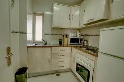 a small kitchen with white cabinets and a sink at Vacation Apartment in Vilamoura in Quarteira