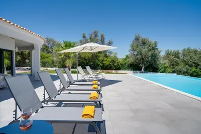 a row of lounge chairs next to a swimming pool at Quinta do Cerro in Loulé
