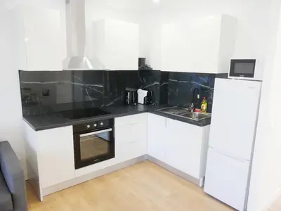 a kitchen with white cabinets and a black counter top at Romao Marina Vilamoura in Quarteira