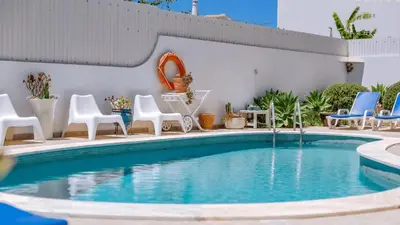 a swimming pool with chairs and a table at Villa Rique in Albufeira