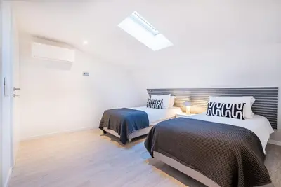 two beds in a room with white walls and wood floors at Old Town Charm Apartment in Albufeira