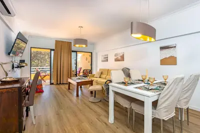 a dining room and living room with a table and chairs at 2 Bed-Sleeps 4-Vilamoura Beach-Pool-Spa-Balcony in Quarteira