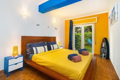 a bedroom with a yellow bed with two towels on it at Sardinha Beach House in Olhos de Água