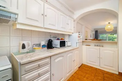 a kitchen with white cabinets and a counter with a microwave at Sardinha Beach House in Olhos de Água
