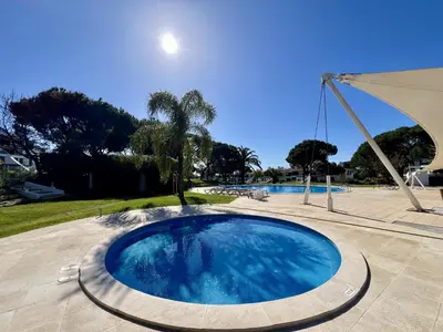 a large swimming pool with an umbrella in a yard at Vilamoura Sunny Garden With Pool by Homing in Vilamoura
