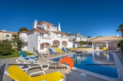 a villa with a swimming pool with chairs and a house at #288 Vivenda 3 Palmeiras 57 by Home Holidays in Albufeira