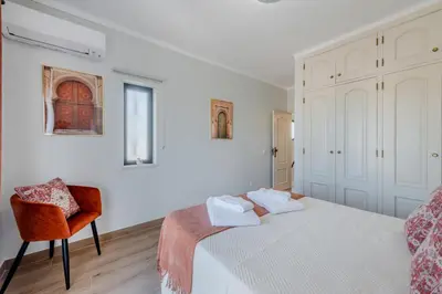 a white bedroom with a bed and a chair at Casa Maré Viva in Guia