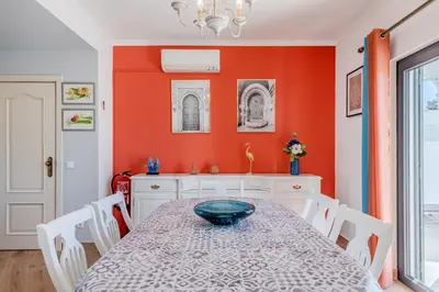 a dining room with orange walls and a table and chairs at Casa Maré Viva in Guia