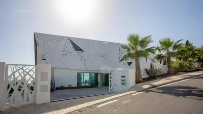 a white building with palm trees in front of it at Algarve Villa for Contemporary Design & Sea Views in Albufeira