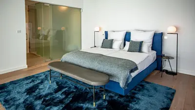 a bedroom with a large bed with a blue rug at Algarve Villa for Contemporary Design & Sea Views in Albufeira