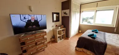 a bedroom with a flat screen tv and a bed at Studio on Maria Luisa Beach Wifi Parking Swimming Pool in Olhos de Água