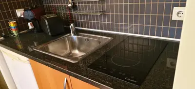 a kitchen counter with a stainless steel sink at Studio on Maria Luisa Beach Wifi Parking Swimming Pool in Olhos de Água