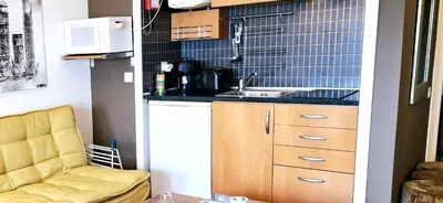 a small kitchen with a sink and a couch at Studio on Maria Luisa Beach Wifi Parking Swimming Pool in Olhos de Água