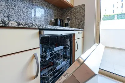 a kitchen with a stainless steel refrigerator and a table at BnB Homes White Rose Garden Apartment with 2 Terraces & 2 Swimming Pools in Albufeira